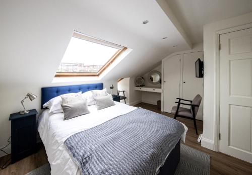 a bedroom with a bed with a blue headboard and a window at Wimbledon Park Bed & Breakfast in London