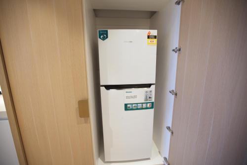a white refrigerator in a room next to a door at Box Hill Central Sky One Apartment in Box Hill