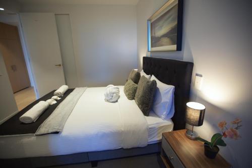 a bedroom with a bed with white sheets and pillows at Box Hill Central Sky One Apartment in Box Hill
