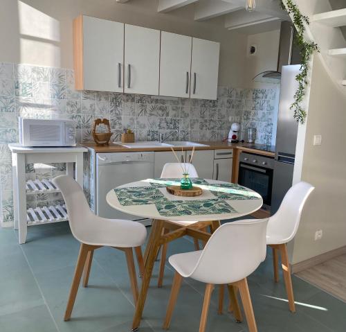 a kitchen with a table and white chairs at Appt Ambiance Exotique 2 ch Piscine lagon in Tarbes