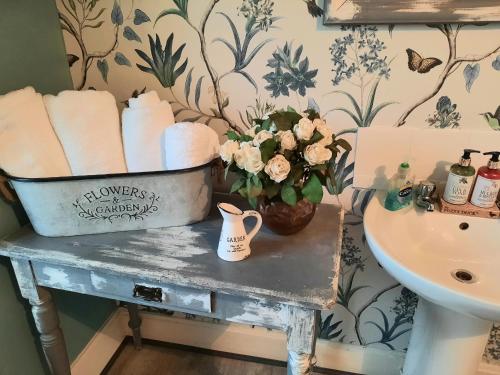 a bathroom with a table with towels and a sink at Argyle Guest House in Tomintoul