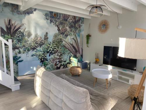 a living room with a couch and a mural of plants at Appt Ambiance Exotique 2 ch Piscine lagon in Tarbes