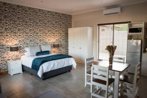 a bedroom with a bed and a table and a kitchen at Sol Montis Guest Cottage in Paarl