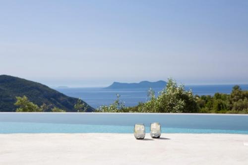 Fternón的住宿－High-end Villa Faos "One"，两双白鞋坐在海滩上靠近水面