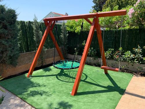 a swing set on the grass in a garden at Villa KRK-4 bedrooms, 4 bathrooms with heated pool and jacuzzi, 150m from the sea in Krk
