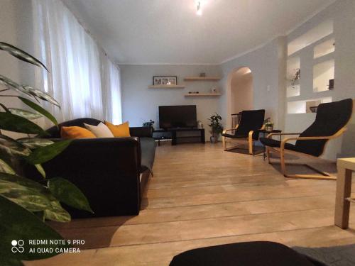 uma sala de estar com um sofá e cadeiras e uma televisão em Felhő Apartman em Balatonfüred