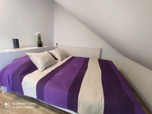 a purple and white bed in a white room at Felhő Apartman in Balatonfüred