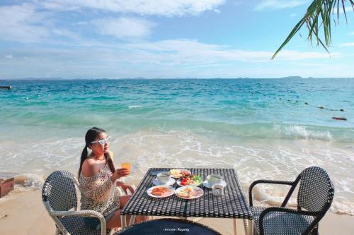 a woman sitting at a table with a meal on the beach at Samed Seaside Resort in Ko Samed