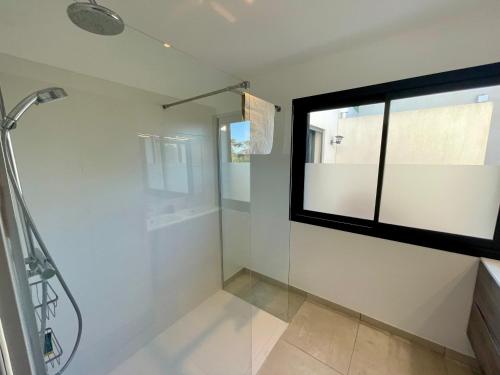 La salle de bains est pourvue d'une douche et d'une fenêtre. dans l'établissement Appartement luxe Le Levant, à Hyères