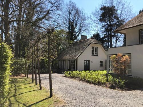 uma casa branca com telhado de palha em Schilde Cottage em Schilde