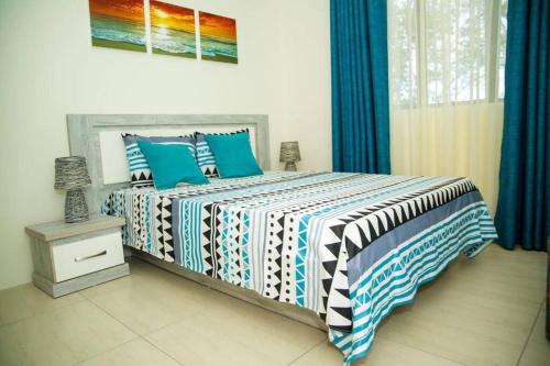 a bedroom with a bed with blue and white blankets and pillows at Entire Luxury 3 BR condo for rent - Flic-en-Flac - Close to Beach in Flic-en-Flac