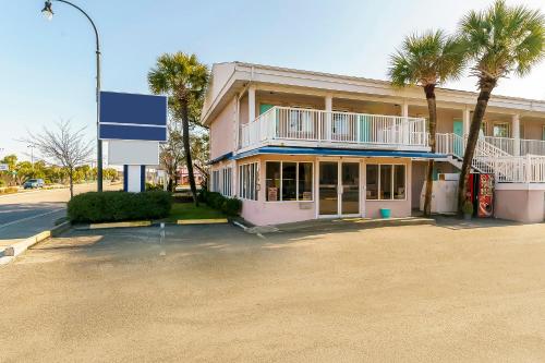 różowy budynek z palmami przed nim w obiekcie OYO Hotel Myrtle Beach Kings Hwy w mieście Myrtle Beach
