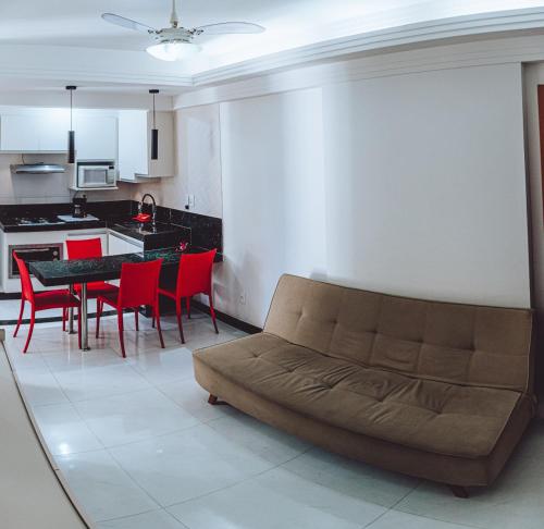 ein Wohnzimmer mit einem Sofa und einem Tisch mit roten Stühlen in der Unterkunft 100 metros da praia das Castanheiras,com garagem, internet, cadeiras de praia, cooler,roupas de cama e banho in Guarapari