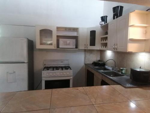 a kitchen with a stove and a white refrigerator at El Castillo Monte Campana in Puntarenas
