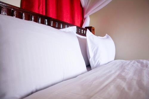 a bed with white pillows and a red curtain at Turbine Ngong Hotel in Ngong