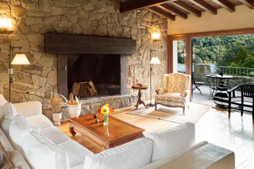 a living room with a stone fireplace and white couches at Aldebaran Hotel & Spa in San Carlos de Bariloche