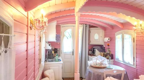 Cette chambre rose comprend une table et un lavabo. dans l'établissement Bungalow cosy à Bussac-Forêt avec piscine partagée 15 m², à Bussac-Forêt