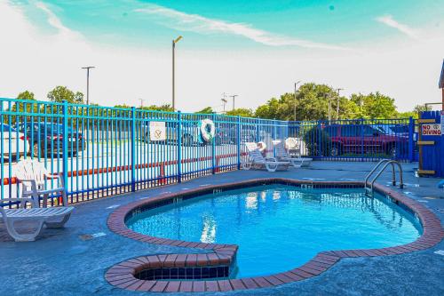 a swimming pool in a playground with a blue fence at OYO Hotel Irving DFW Airport South in Irving