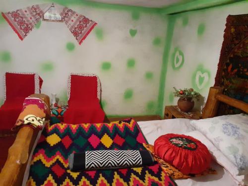a bedroom with a bed with colorful blankets and pillows at RUSTIC SEJOUR,Roşia Montana in Roşia Montană