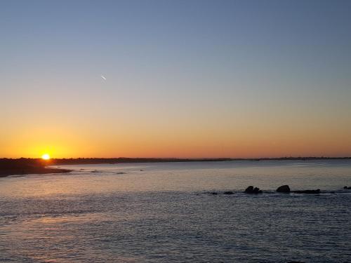 a sunset over a body of water with rocks in the water at Ty Theven in Plouescat