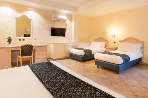 a hotel room with two beds and a desk at Sant Alphio Garden Hotel & SPA in Giardini Naxos