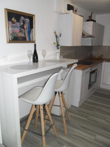 a kitchen with two white chairs at a counter at Mirta in Stara Baška