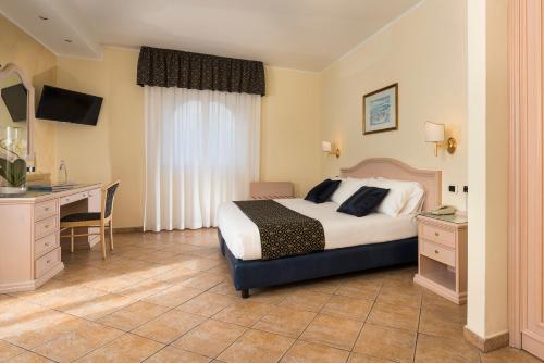 a hotel room with a bed and a desk and a television at Sant Alphio Garden Hotel & SPA in Giardini Naxos