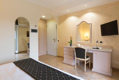 a bedroom with a desk and a bed with a mirror at Sant Alphio Garden Hotel & SPA in Giardini Naxos
