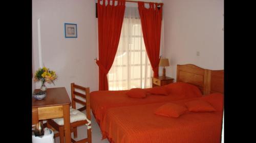 1 Schlafzimmer mit 2 Betten, einem Tisch und einem Fenster in der Unterkunft Apartamento na praia do Carvoeiro in Carvoeiro