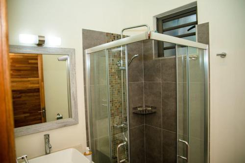 a bathroom with a glass shower with a sink at Entire Luxury 3 BR condo for rent - Flic-en-Flac - Close to Beach in Flic-en-Flac