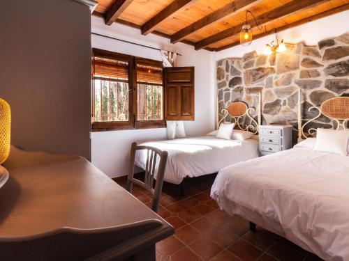 een kamer met 2 bedden en een stenen muur bij Cortijo rincón del sur in Nigüelas