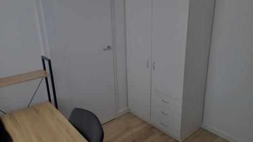 a room with white cabinets and a table and a chair at City center apartment in Alytus