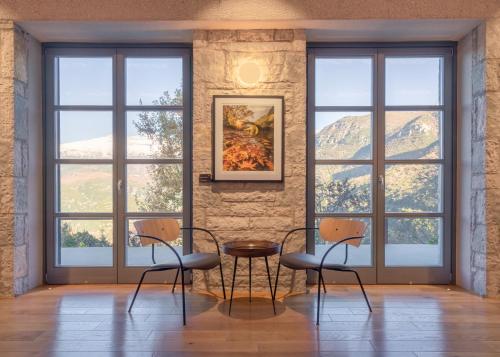 a room with three chairs and a table in front of windows at Aristi Mountain Resort in Aristi
