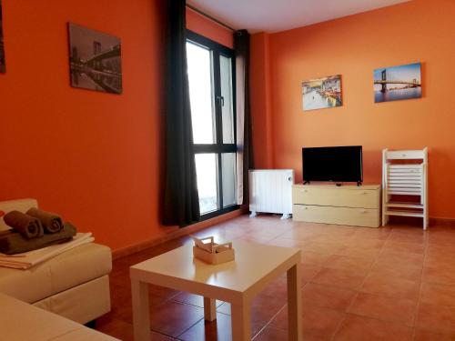 a living room with orange walls and a table and a tv at Apartamentos Monte Gorbea con parking y WiFi by SURYNIEVE in Sierra Nevada