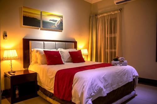 a bedroom with a large bed with red and white sheets at The Pillows Suite in Pretoria