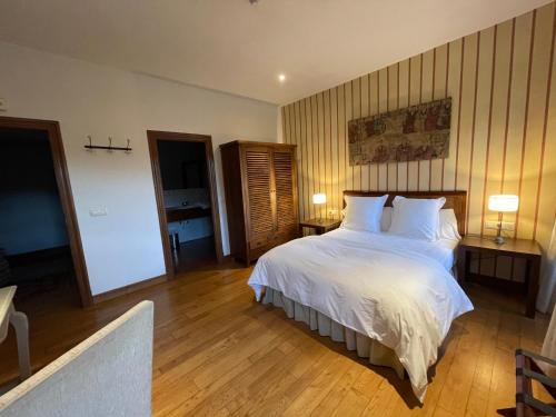 a bedroom with a large bed with white sheets and pillows at Rectoral de Cines in Oza dos Ríos