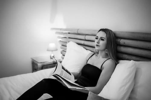 a woman sitting on a bed reading a book at Domaine des Bois Argentés in Saugirard