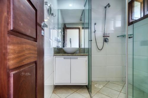 a bathroom with a glass shower and a sink at Unidades Vilas Triplex no Pipa Beleza in Pipa
