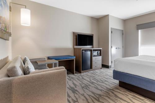 a hotel room with a bed a couch and a tv at Best Western Plus Castlerock Inn & Suites in Bentonville