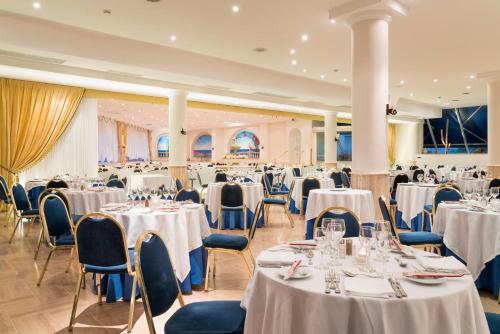 a banquet hall with white tables and chairs at Sant Alphio Garden Hotel & SPA in Giardini Naxos