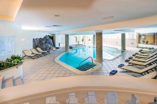 a pool in a hotel with lounge chairs at Sant Alphio Garden Hotel & SPA in Giardini Naxos