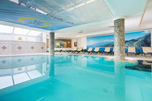 a pool in a hotel with tables and chairs at Sant Alphio Garden Hotel & SPA in Giardini Naxos