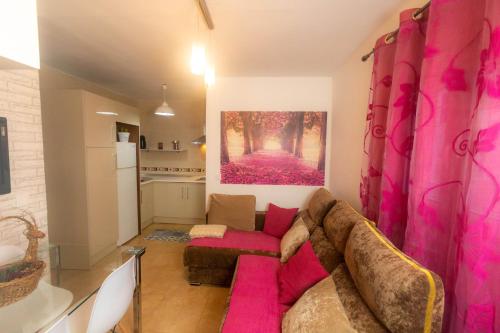 uma sala de estar com um sofá rosa e uma cozinha em Casa de las Flores Cazorla em Cazorla