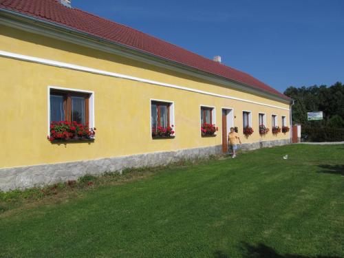 a woman walking in front of a yellow building at Pension Otěvěk in Trhové Sviny
