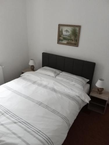 a large bed with white sheets and a black headboard at Apartman Marija in Zlatibor
