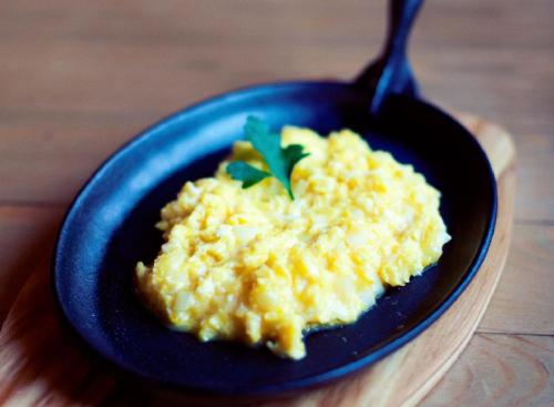 a blue plate of scrambled eggs with a spoon at Chata Starych Znajomych in Sanok