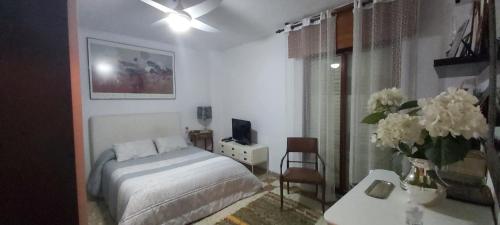 Un dormitorio con una cama y una mesa con un jarrón de flores en lola.- HABITACION DE MATRIMONIO, CON BAÑO PRIVADO, en Granada
