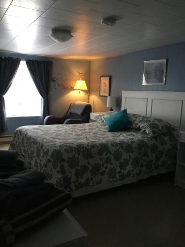 une chambre d'hôtel avec un lit et une chaise dans l'établissement Gîte la Veilleuse, à Saint-Georges-de-Cacouna