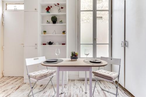 uma sala de jantar branca com uma mesa e cadeiras brancas em L'emplacement Idéal - Tour Eiffel 10min - NETFLIX - em Paris