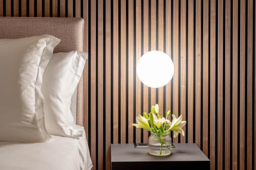 a vase of flowers on a table next to a bed at Smart Hotel Binario - Self Check-In in Locarno